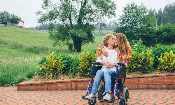 Жінка в інвалідному візку цілує свою дочку — стокове фото