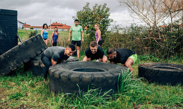 Participants in an obstacle course turning a wheel