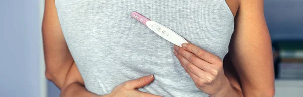 Paar umarmt sich, während Frau Hand in Hand Schwangerschaftstest hält — Stockfoto