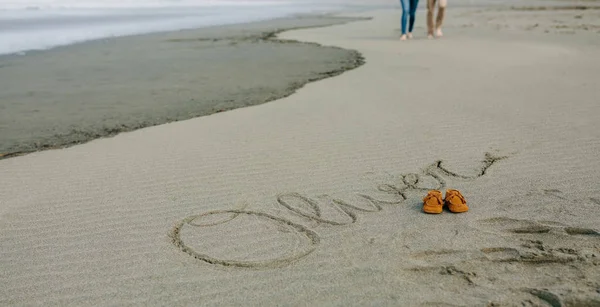 Nom de bébé écrit en sable avec des chaussures — Photo