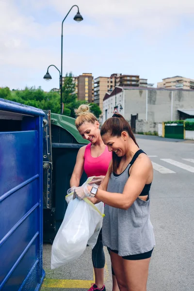 Chicas arrojando basura al contenedor de reciclaje — Foto de Stock