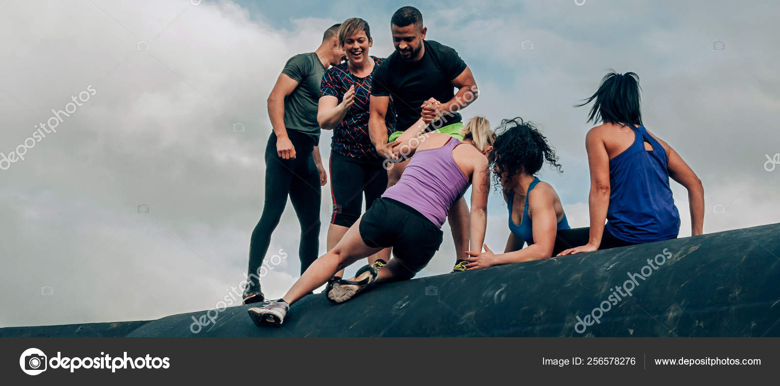 Participantes en carrera de obstáculos escalando un tambor — Foto de stock  #256578276 © doble.dphoto, image size:1600x792