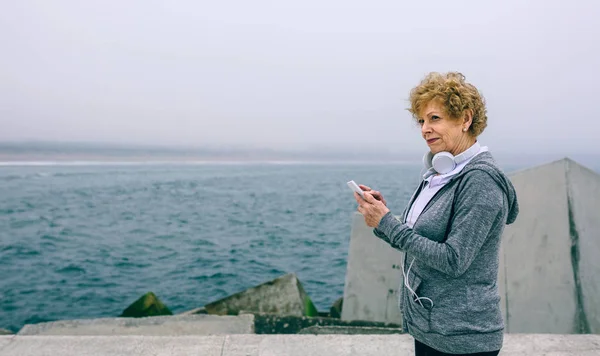 Senior sportswoman using her smartphone — Stock Photo, Image