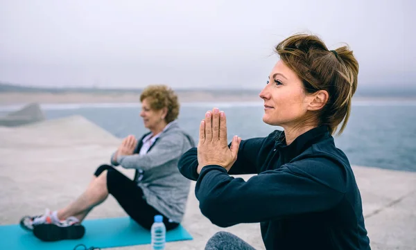 Mujeres ejercitándose en un muelle de concreto — Foto de Stock