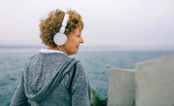 Seniorin mit Kopfhörer schaut zur Seite — Stockfoto