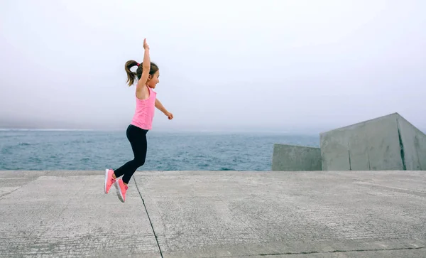 Klein meisje springen door zee Pier — Stockfoto