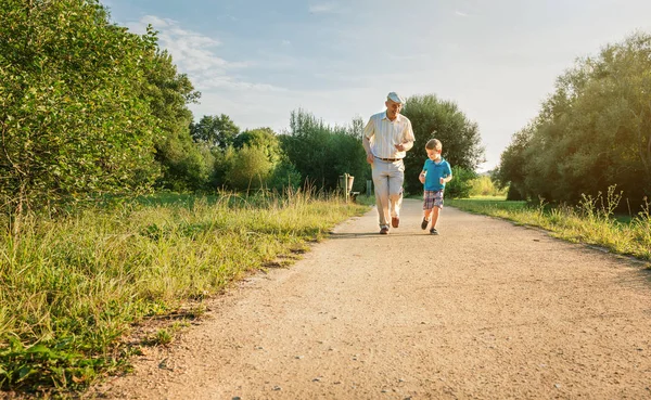 Senior man and happy child running outdoors — Stock Photo, Image