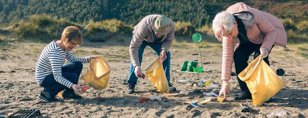 Ältere Freiwillige säubern den Strand — Stockfoto