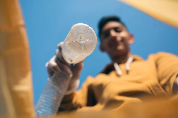 젊은 남자가 쓰레기통에 플라스틱 병을 던져 넣는 모습 — 스톡 사진