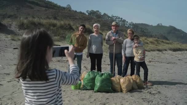 Menina tirando foto para grupo de voluntários após a limpeza da praia — Vídeo de Stock