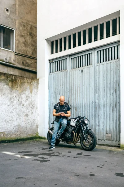 Biker patrząc mobilnych, siedząc na motocykl — Zdjęcie stockowe