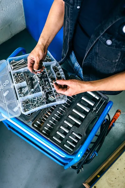 Las manos del mecánico eligen tornillos de una caja de herramientas — Foto de Stock