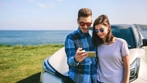 Pareja con coche mirando móvil —  Fotos de Stock