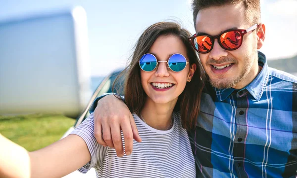 Young couple doing a selfie on the car — Stock Photo, Image