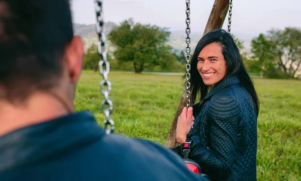 Happy young woman looking camera sitting on a swing — Stock Photo, Image