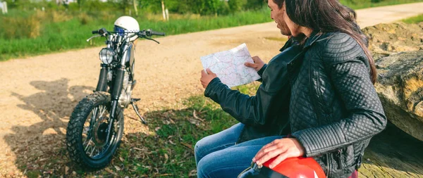 Pár sedí a dívá se na mapu s motocyklem — Stock fotografie