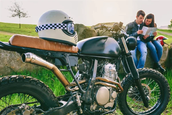Обычный мотоцикл с шлемом и молодой парой, смотрящей на карту — стоковое фото