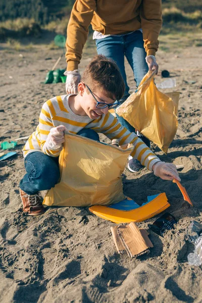 Jonge vrijwilligers die het strand schoonmaken — Stockfoto