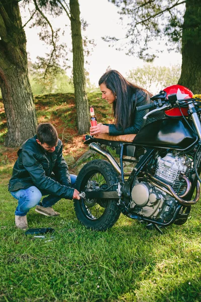 Uomo fissaggio sua moto mentre la sua ragazza lo guarda — Foto Stock