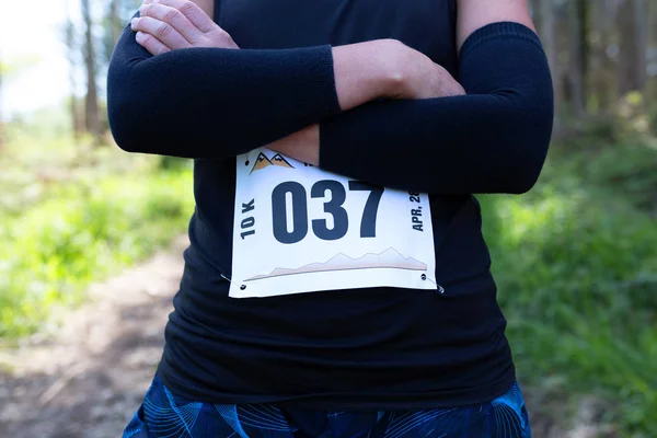 Oigenkännlig kvinnliga trail idrottsman poserar med nummerlappen — Stockfoto