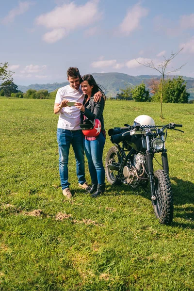 Coppia cercando mobile con una moto — Foto Stock