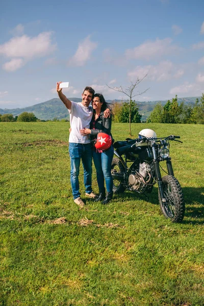 Pareja tomando una selfie con una motocicleta — Foto de Stock