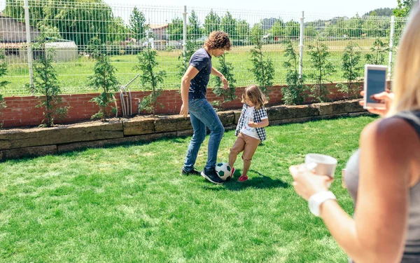 Mother taking photo of her husband and son playing — Stock Photo, Image