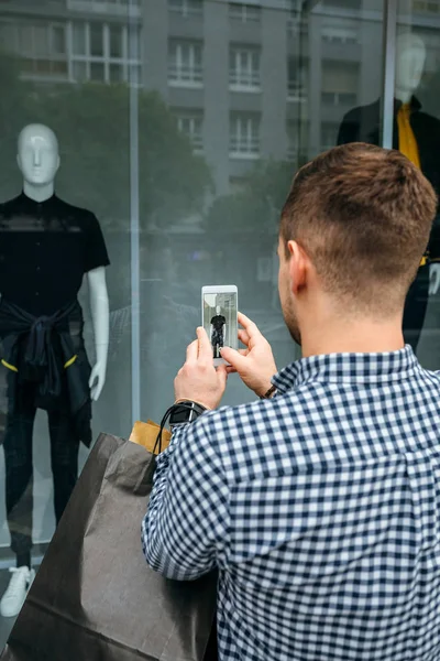 Homem tirando uma foto de uma vitrine de uma loja de moda — Fotografia de Stock