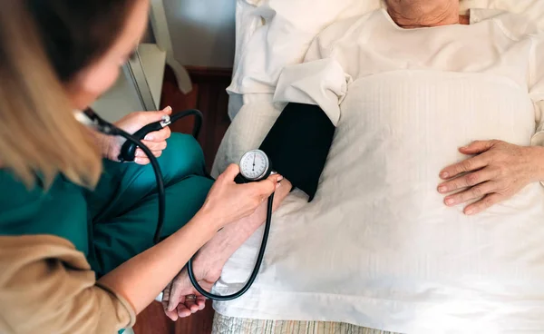 Cuidador revisando la presión arterial de una mujer mayor — Foto de Stock