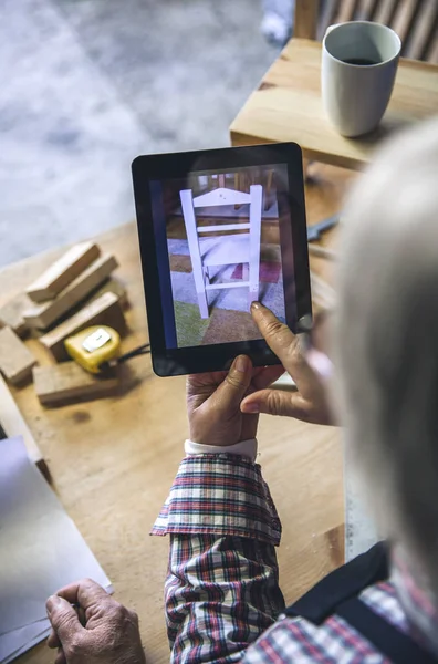 Mulher idosa irreconhecível em uma carpintaria procurando tablet — Fotografia de Stock