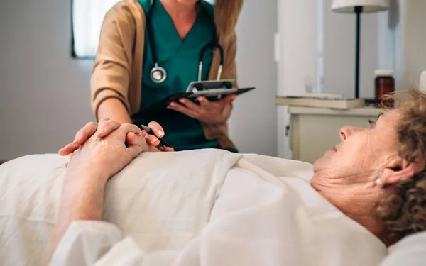 Médico feminino reconfortante paciente mais velho — Fotografia de Stock