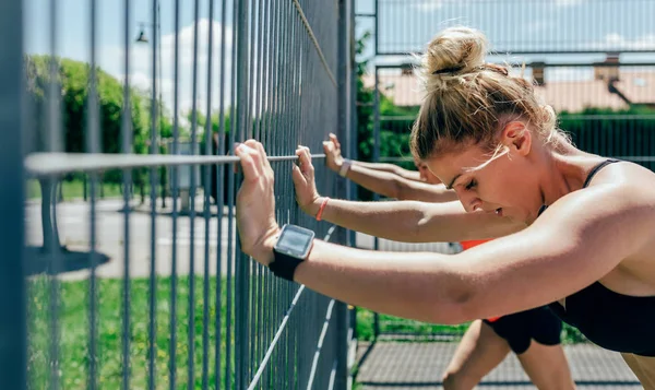 Zwei Sportlerinnen an Zaun gestützt — Stockfoto