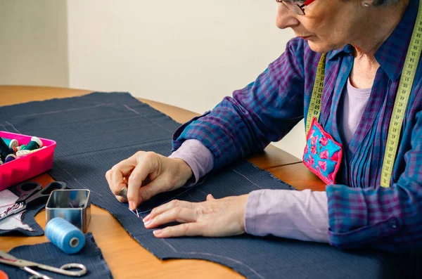 Senior female seamstress sewing cloth — Stock Photo, Image