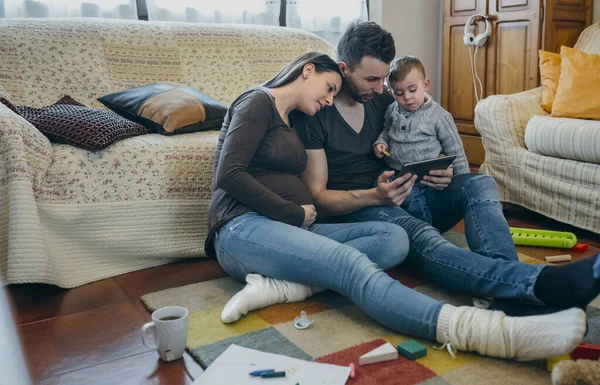 Familj med barn och gravid mor tittar tablett — Stockfoto