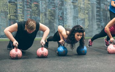 Spor kadınları kettlebell ile şınav çekiyorlar.