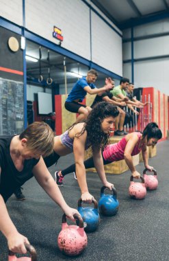 Spor kadınları kettlebell ile şınav çekiyorlar.