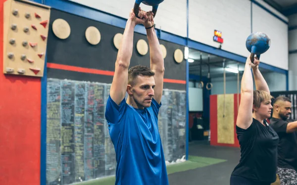 Deportista haciendo ejercicio con Kettlebell con sus socios — Foto de Stock