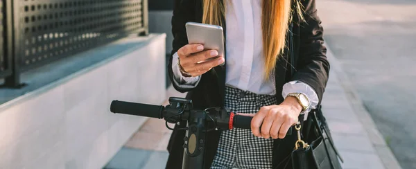 E-scooterlı tanınmayan iş kadını cep telefonuna bakıyor. — Stok fotoğraf