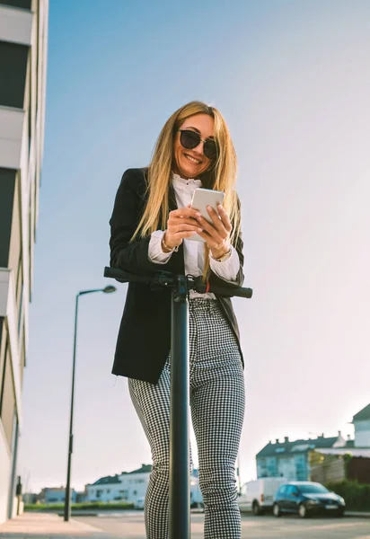 Bizneswoman z skuterem elektrycznym patrząc na telefon — Zdjęcie stockowe