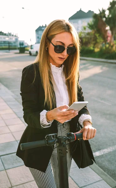 Affärskvinna med e-scooter tittar på mobiltelefon — Stockfoto