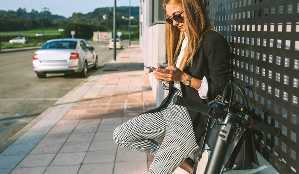 Empresária com celular e sua scooter próxima — Fotografia de Stock