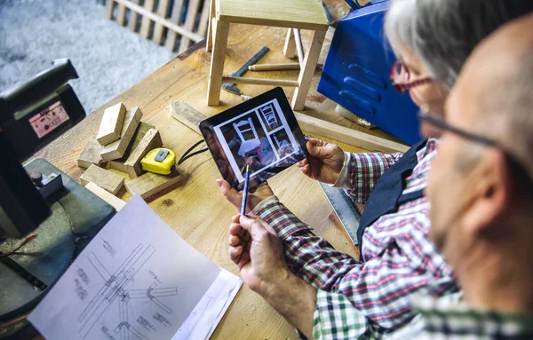 Coppia anziana in una falegnameria alla ricerca di tablet — Foto Stock