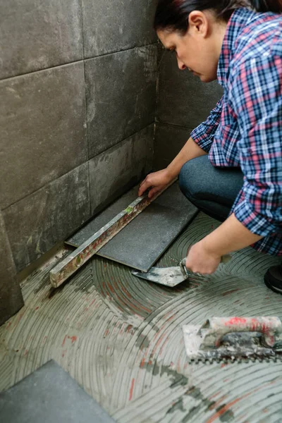 Female bricklayer checking floor with a level — Stock Photo, Image