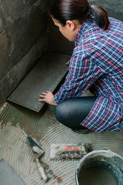 Construtor feminino que estabelece um novo piso de azulejo — Fotografia de Stock