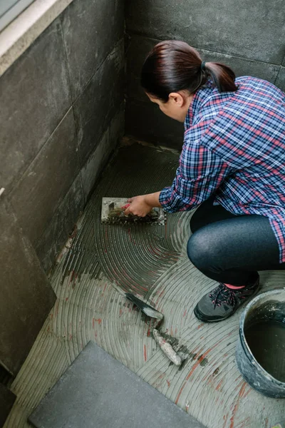 Pedreiro feminino que estabelece um novo piso de azulejo — Fotografia de Stock