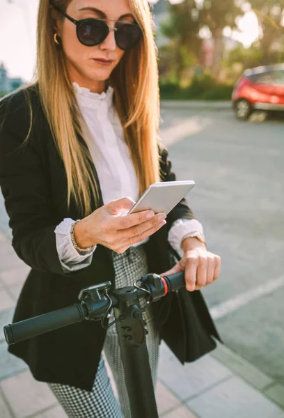 Affärskvinna med e-scooter tittar på mobiltelefon — Stockfoto