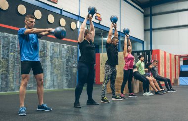 Atletizm sporcuları, çan sesleri eşliğinde spor yapıyor.