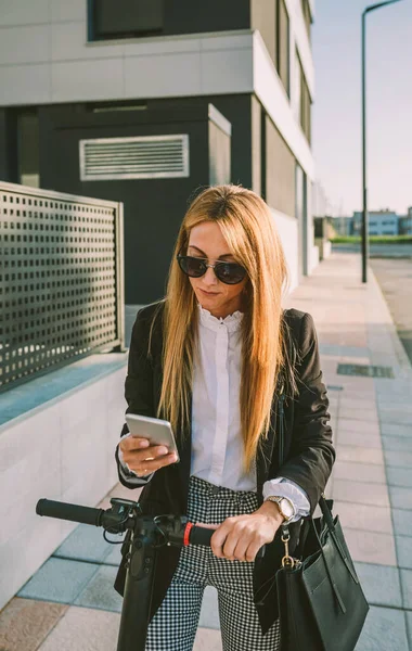 Mujer de negocios con e-scooter mirando el teléfono celular — Foto de Stock