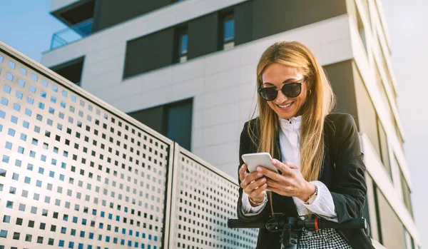 Mujer de negocios con scooter eléctrico mirando al móvil — Foto de Stock