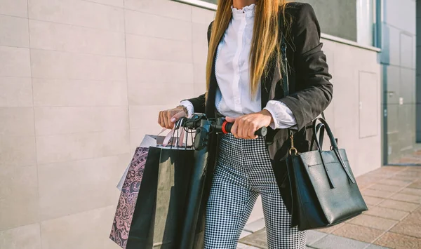 Αγνώριστη γυναίκα με τσάντες ψώνια σε ηλεκτρικά σκούτερ — Φωτογραφία Αρχείου